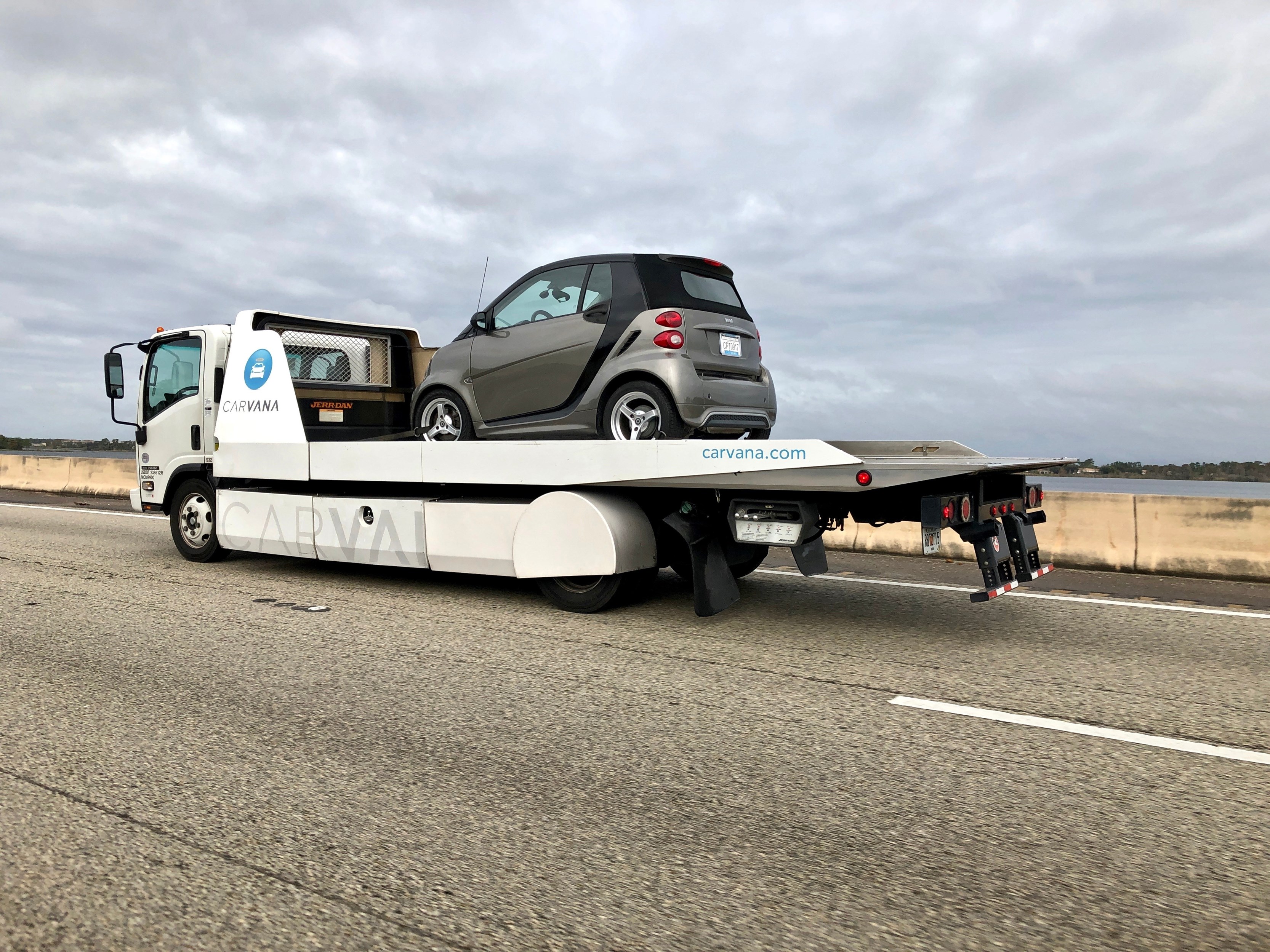 Carvana trucking delivering a used car