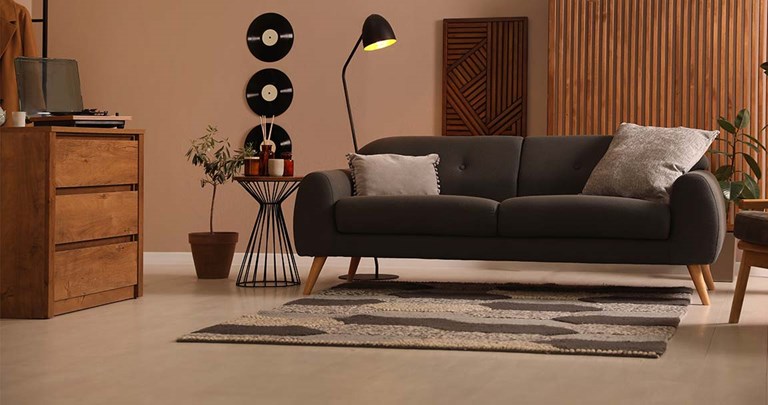 Moody living room with light wood floors, charcoal grey couch and records on the wall 