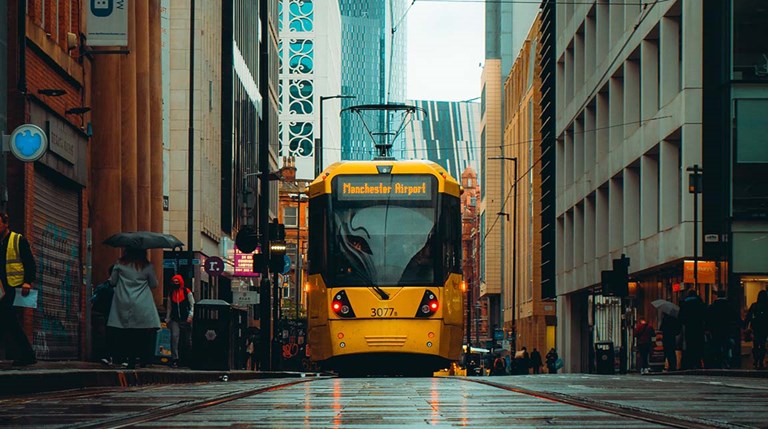 Rainy city of Manchester with front view of a yellow train 