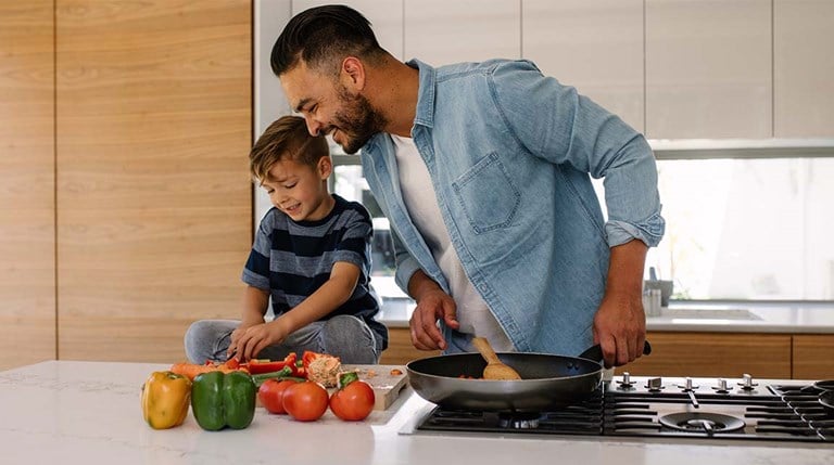 Caucasian male cut colorful vegetables with his young son