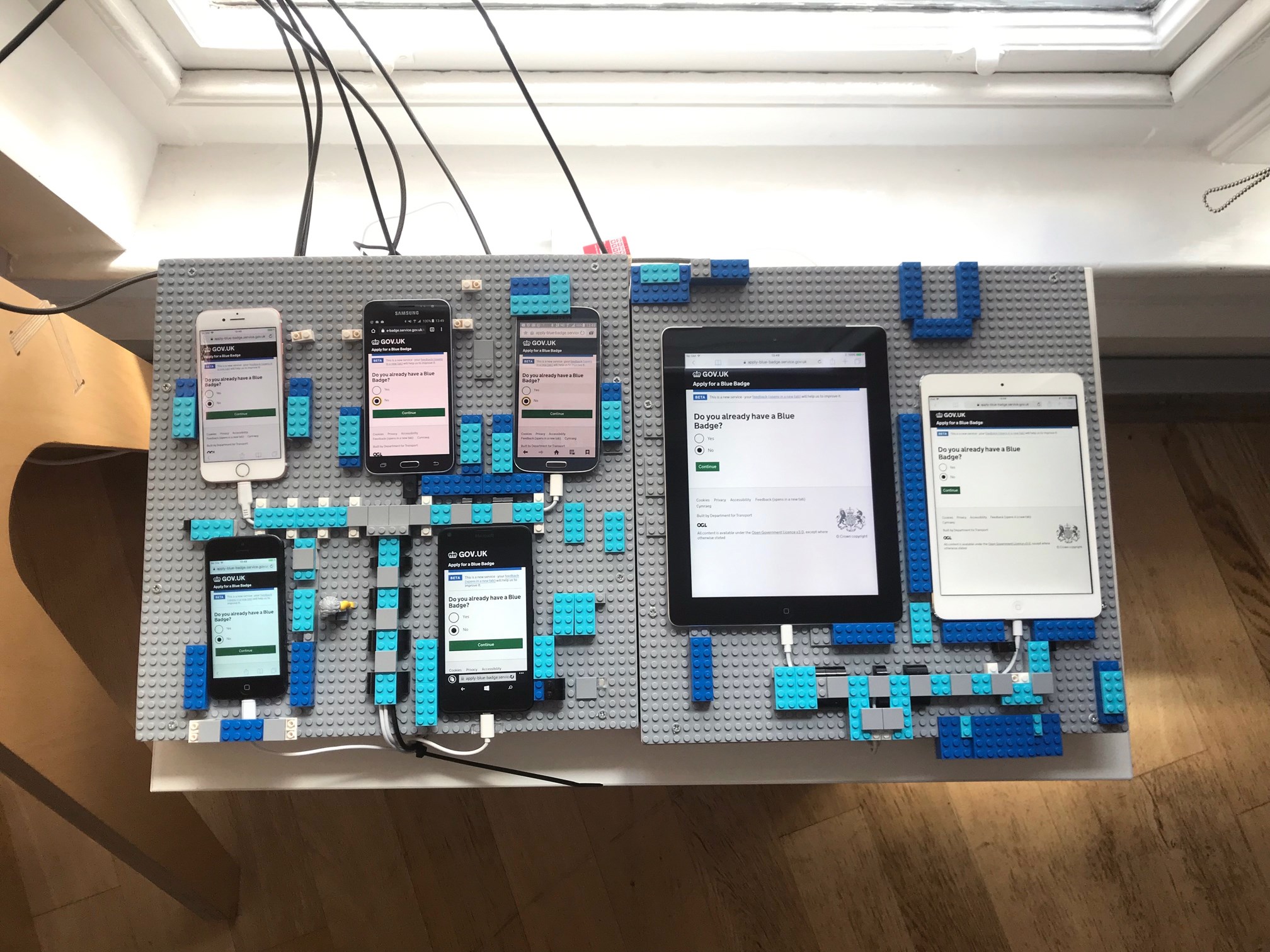 The Blue Badge Digital Transformation team’s device lab in Manchester. The lab consists of: Windows Mobile, Samsung Galaxy S4, Samsung Galaxy S5, iPad mini, iPad, iPhone 5, iPhone 6 and a Dell laptop. The iOS devices come with Voice Over screen reader, and the laptop has JAWS 2018 and Nuance Dragon 15 installed