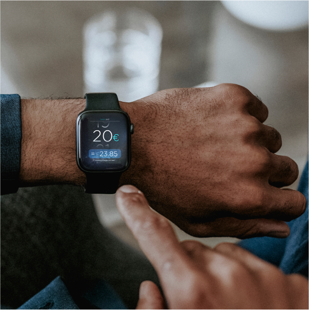 Person checks a smartwatch displaying a digital wallet/payment screen in euros. 