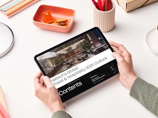 Person holding a tablet displaying Valtech’s Global Travel & Hospitality 2025 Outlook, highlighting industry trends and digital transformation insights.