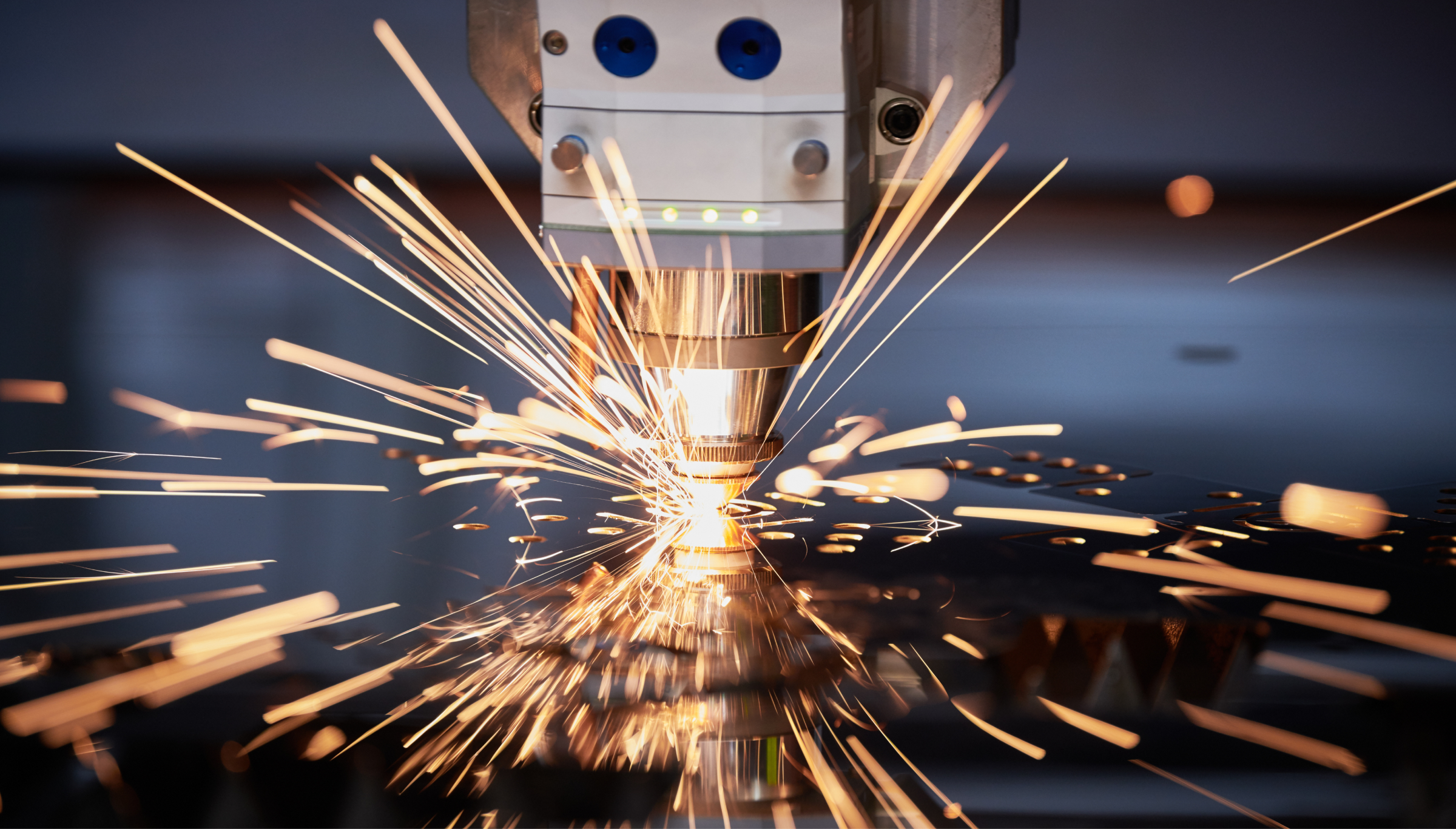 A close-up view of a laser cutting machine in action, emitting bright, golden sparks as it cuts through metal with precision. The machinery is detailed, with sharp focus on the nozzle and spark trails, creating a dynamic industrial scene.