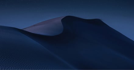 A serene nighttime landscape of desert dunes, softly illuminated under a clear, starry sky. The smooth curves and shadows of the sand create a dramatic, peaceful scene. The image captures the vastness and beauty of the desert under the calmness of night, evoking a sense of solitude and tranquility.