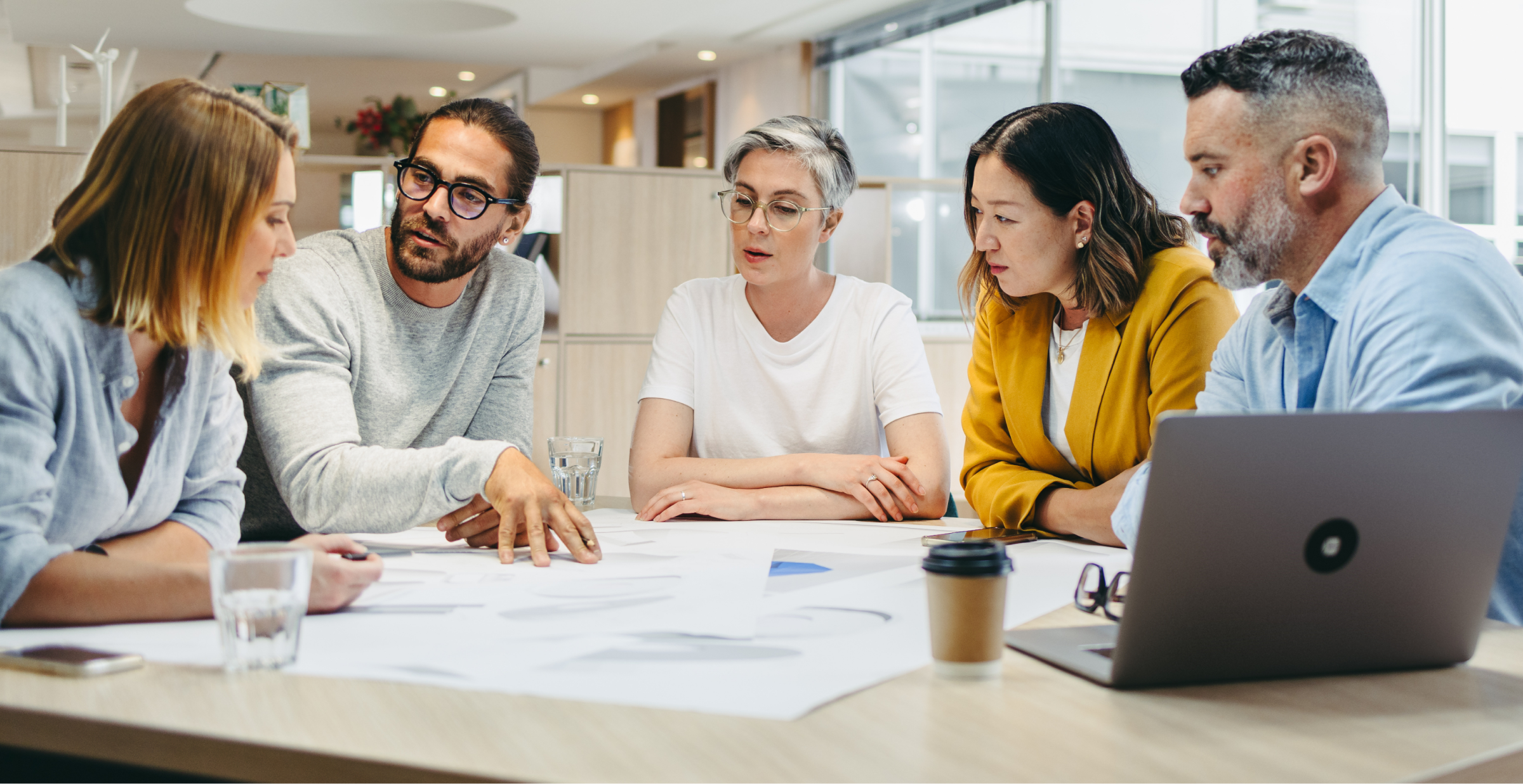 A diverse group of professionals engaged in a collaborative business discussion around a table, highlighting teamwork and innovation.