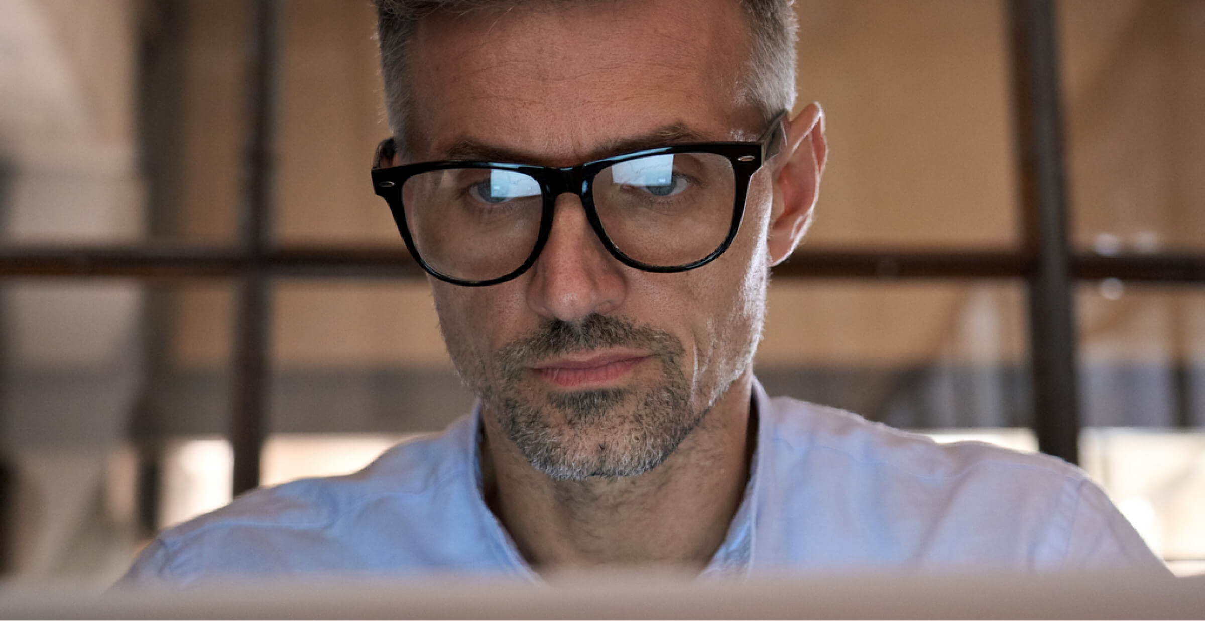 A person sitting at a desk with a computer and a smartphone, reviewing a document titled 'Best Practices for User Interface Design.' The screen shows a detailed wireframe or layout design, with a focus on creating effective user interfaces. The workspace is tidy, with a cup of coffee and a plant in the background.