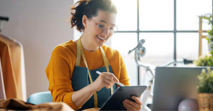 Tailor using a tablet while working in a bright, modern workspace.