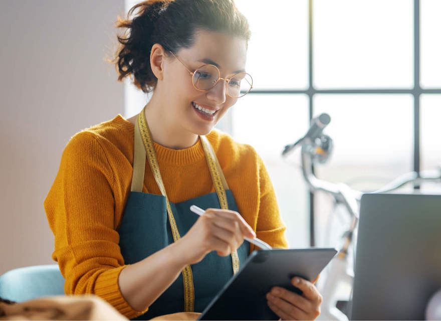 Tailor using a tablet while working in a bright, modern workspace.