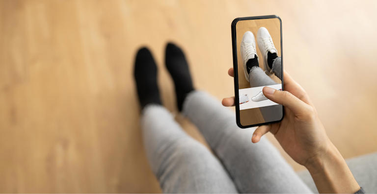 Person using augmented reality on a smartphone to try on shoes virtually.