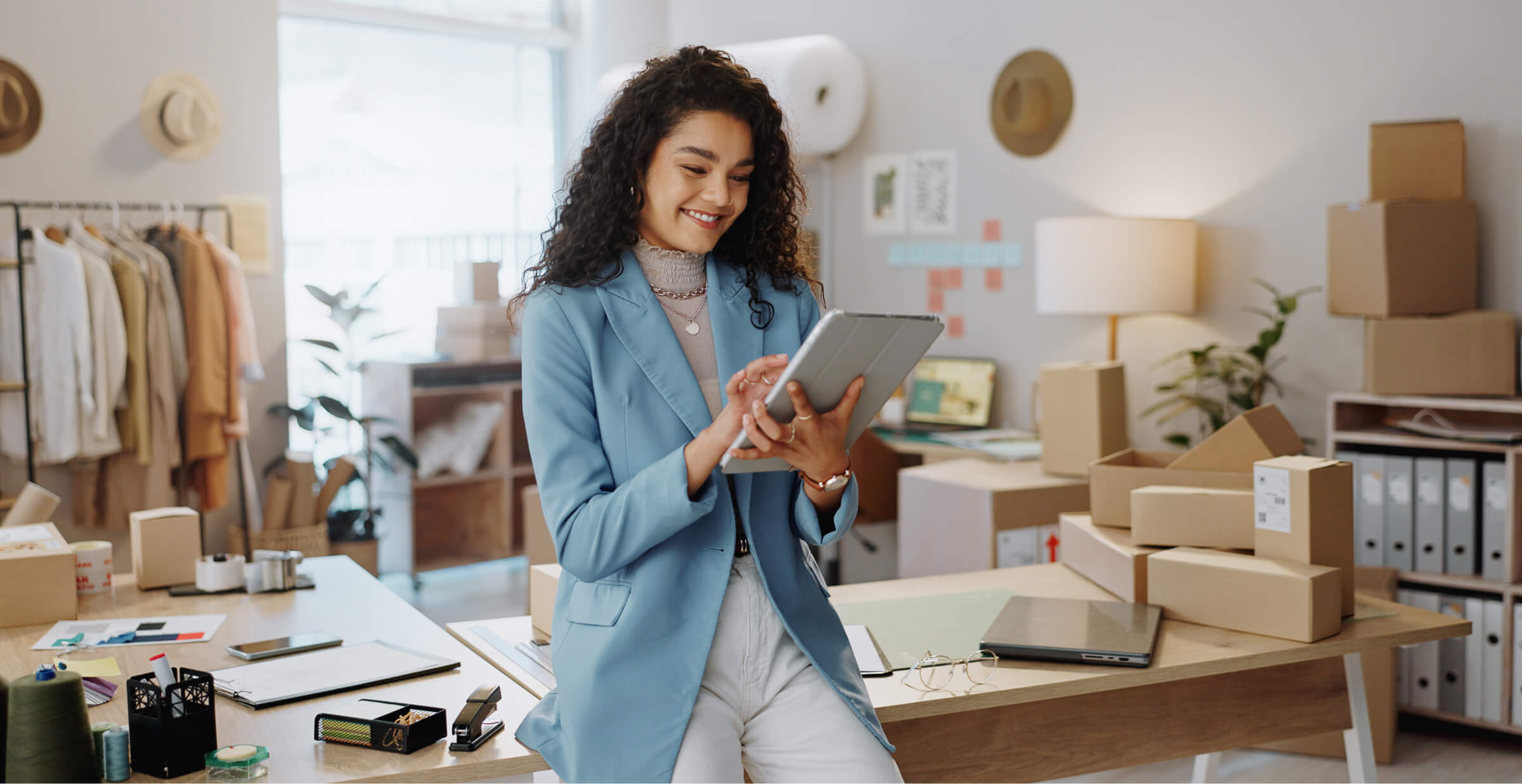 Female entrepreneur managing e-commerce business on a tablet in a home office.
