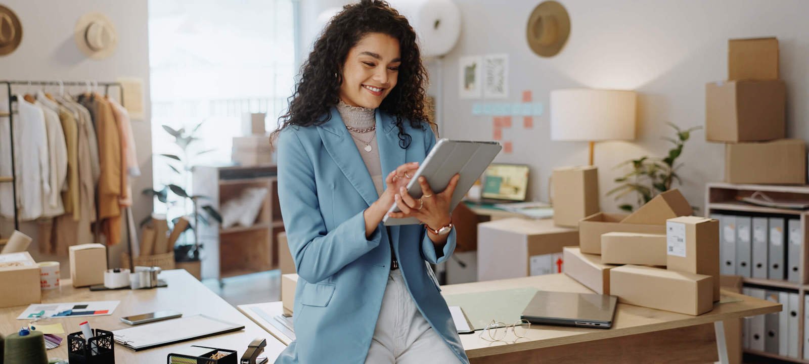 Female entrepreneur managing e-commerce business on a tablet in a home office.