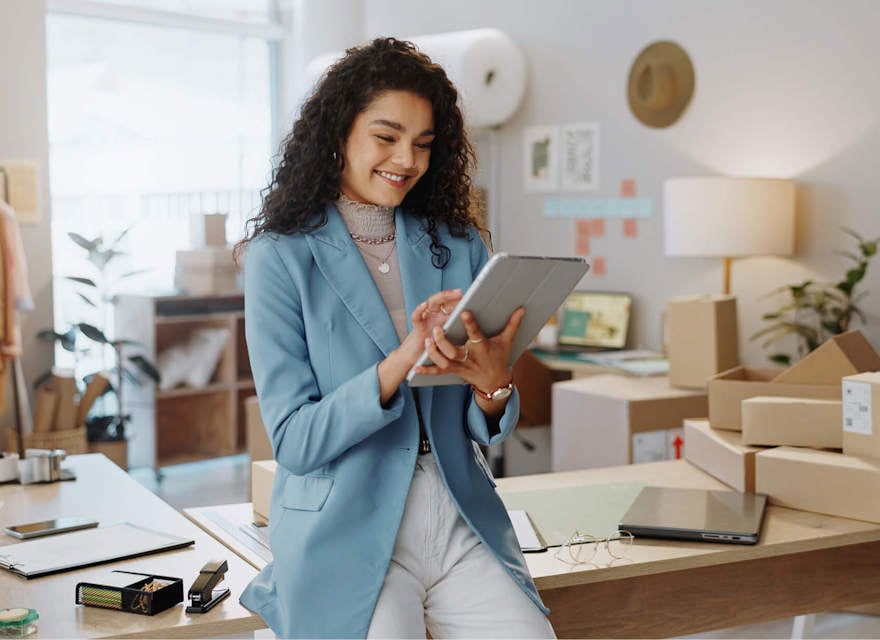 Female entrepreneur managing e-commerce business on a tablet in a home office.