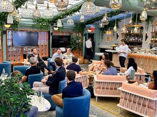 A group of people enjoying a meal together, sitting in chairs at a cozy restaurant.