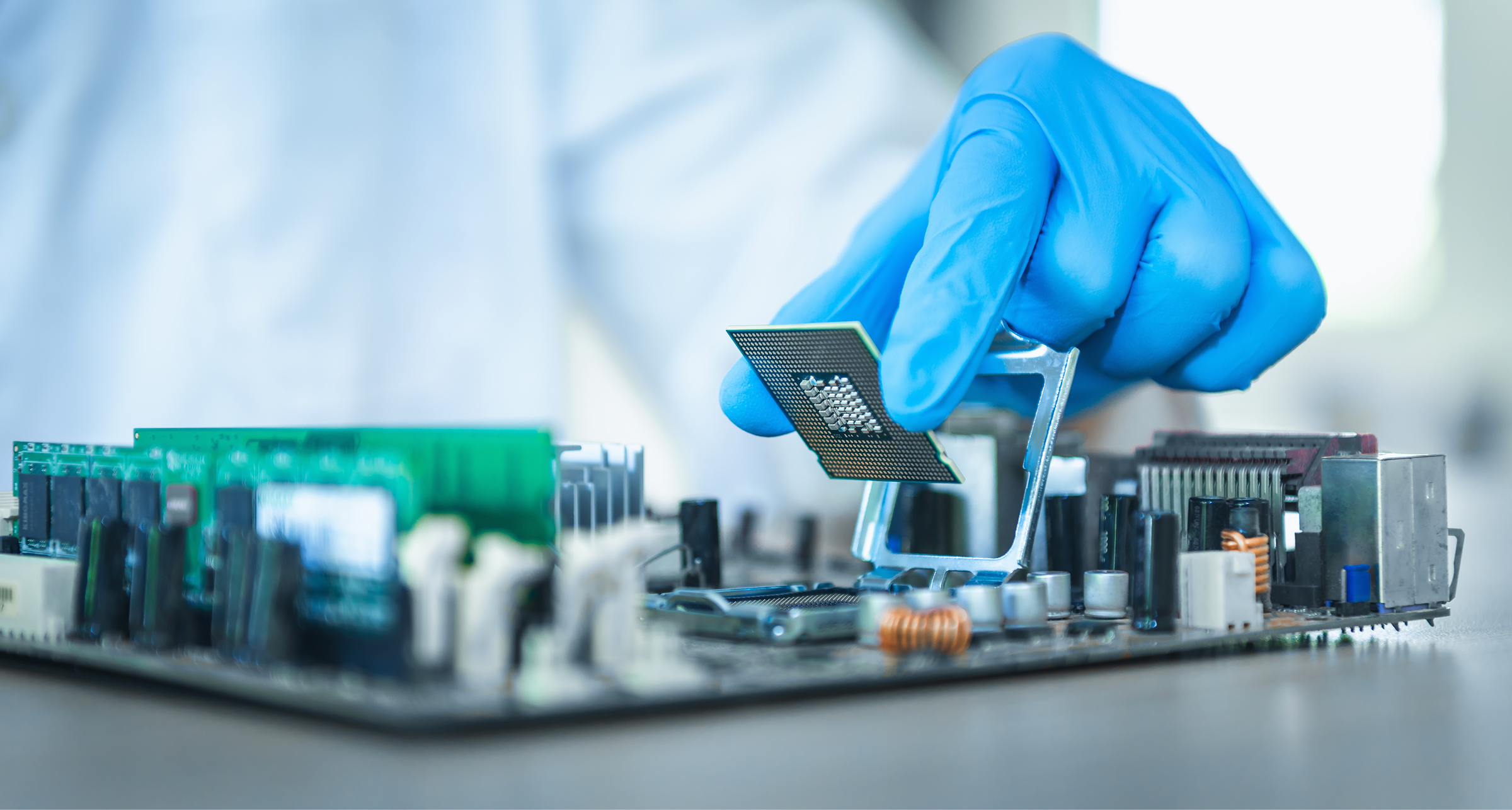 Gloved hand holding a CPU chip above a motherboard socket ready for installation during hardware assembly.