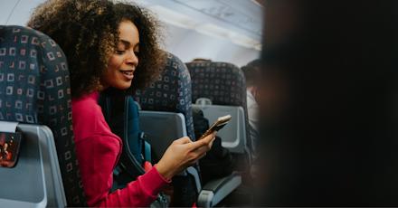 A woman sitting on an airplane, focused on her phone while enjoying her flight