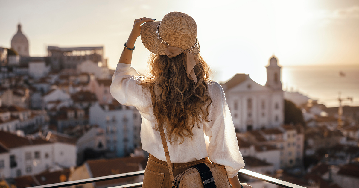 A woman in a stylish hat gazes out over a sprawling cityscape, taking in the view