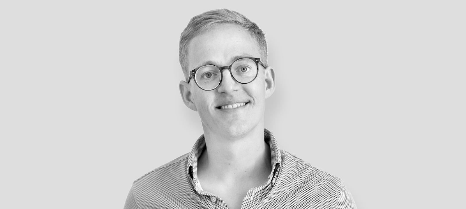 A smiling man wearing glasses and a shirt, exuding a friendly and approachable vibe.