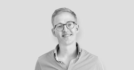 A smiling man wearing glasses and a shirt, exuding a friendly and approachable vibe.