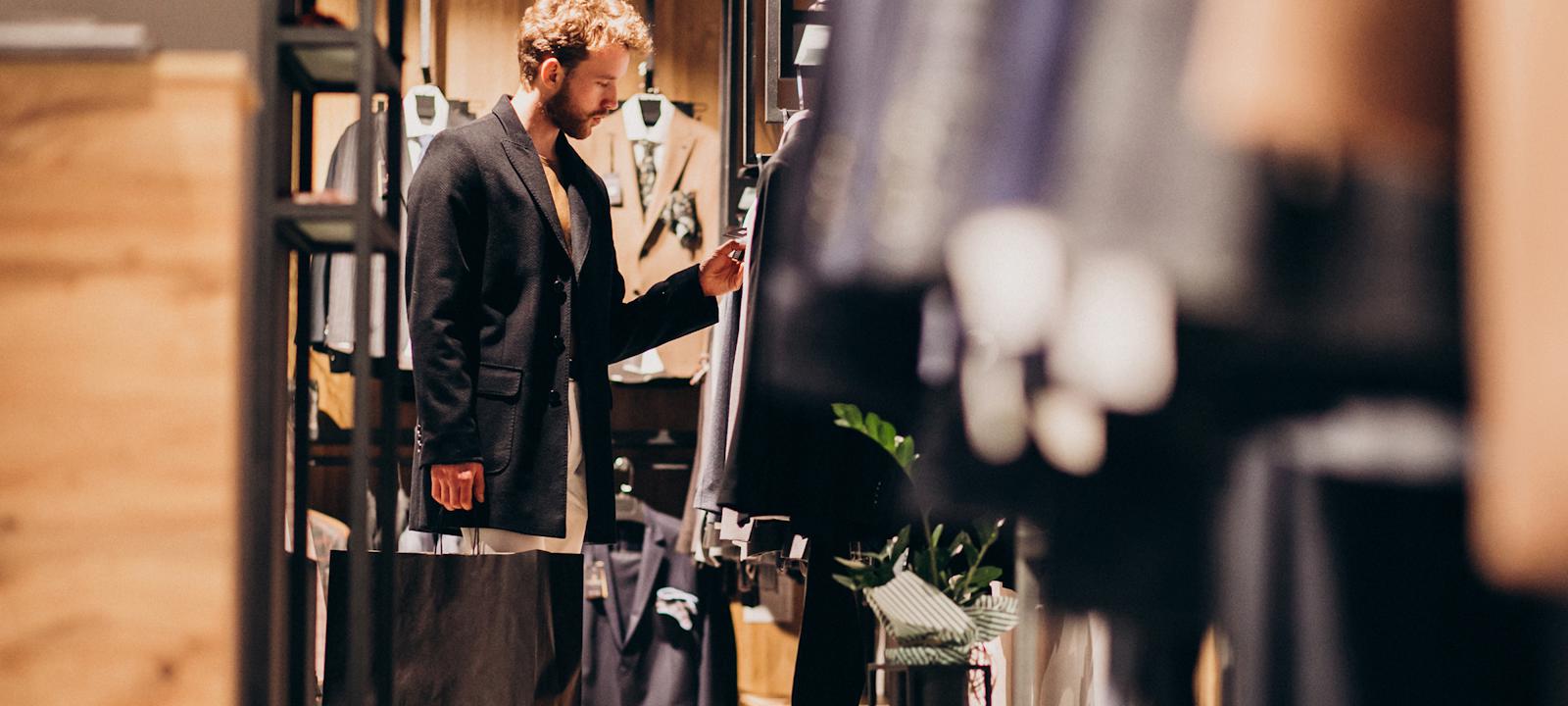 A man examines clothing options while browsing in a clothing store.
