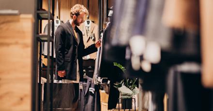A man examines clothing options while browsing in a clothing store.