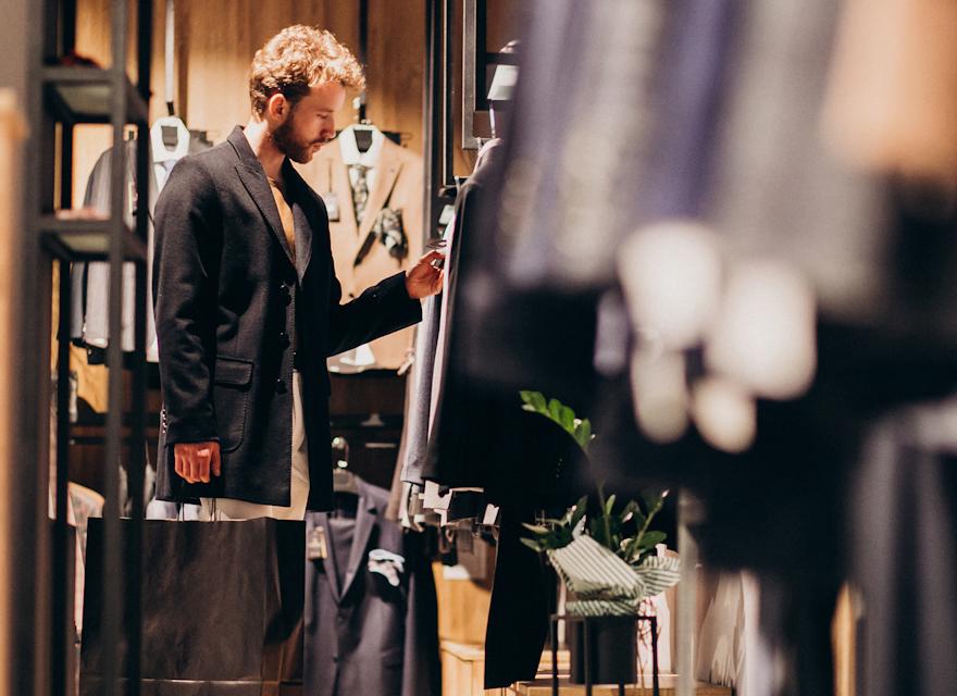 A man examines clothing options while browsing in a clothing store.