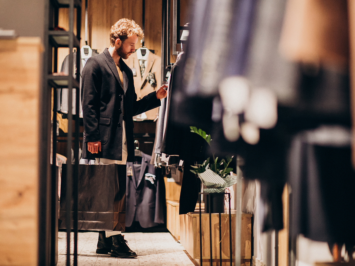 A man examines clothing options while browsing in a clothing store. 