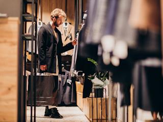 A man examines clothing options while browsing in a clothing store.