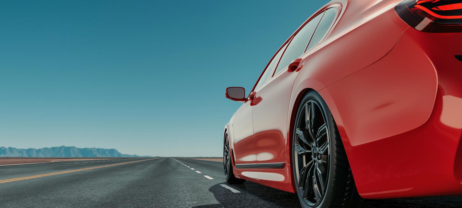 Close-up of a red sports car driving on an open highway under a clear blue sky, representing modern mobility and streamlined digital car experiences.