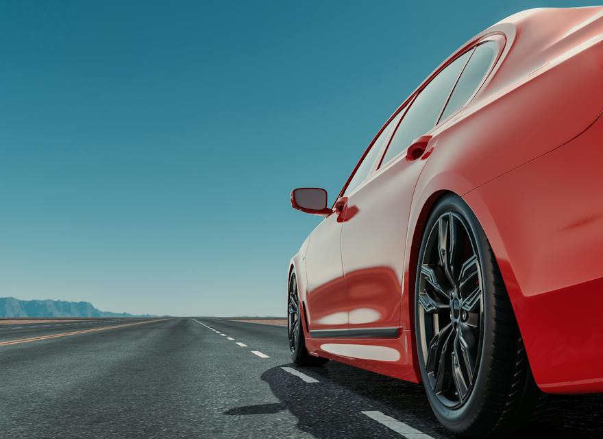 Close-up of a red sports car driving on an open highway under a clear blue sky, representing modern mobility and streamlined digital car experiences.