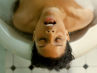 A woman relaxing in a bathtub, surrounded by bubbles and candles, enjoying a moment of tranquility