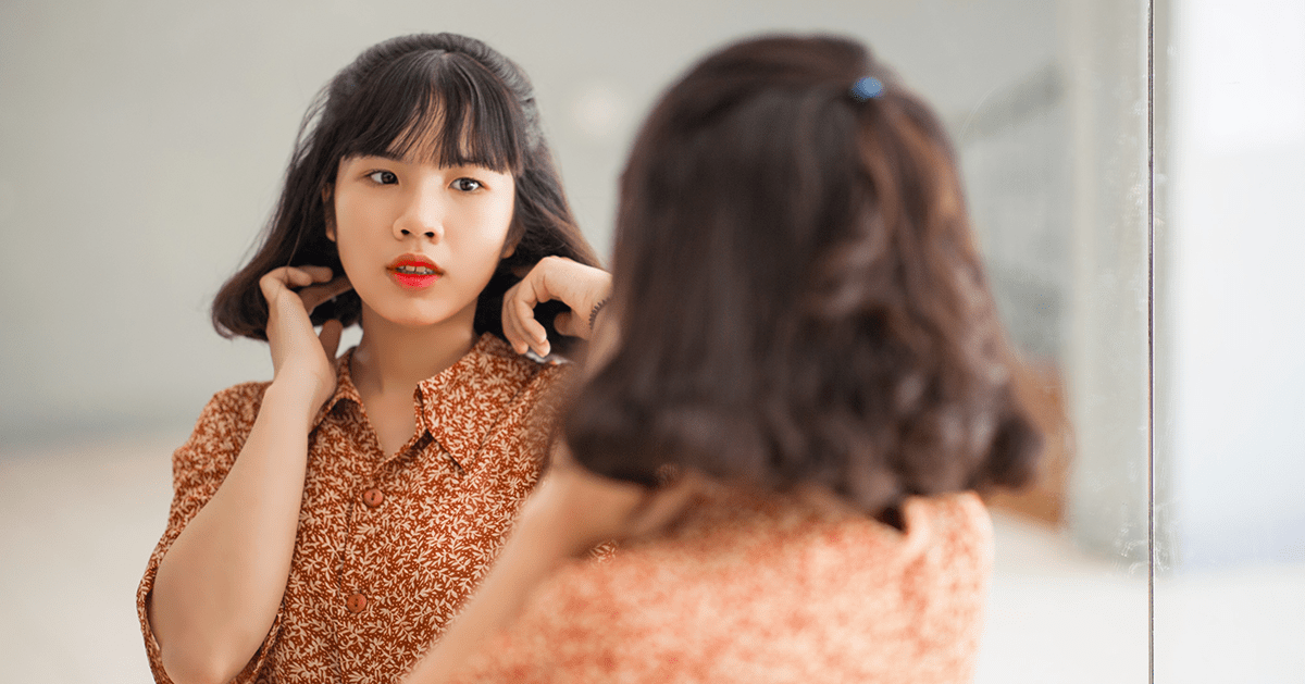 Asian woman looking at herself in mirror