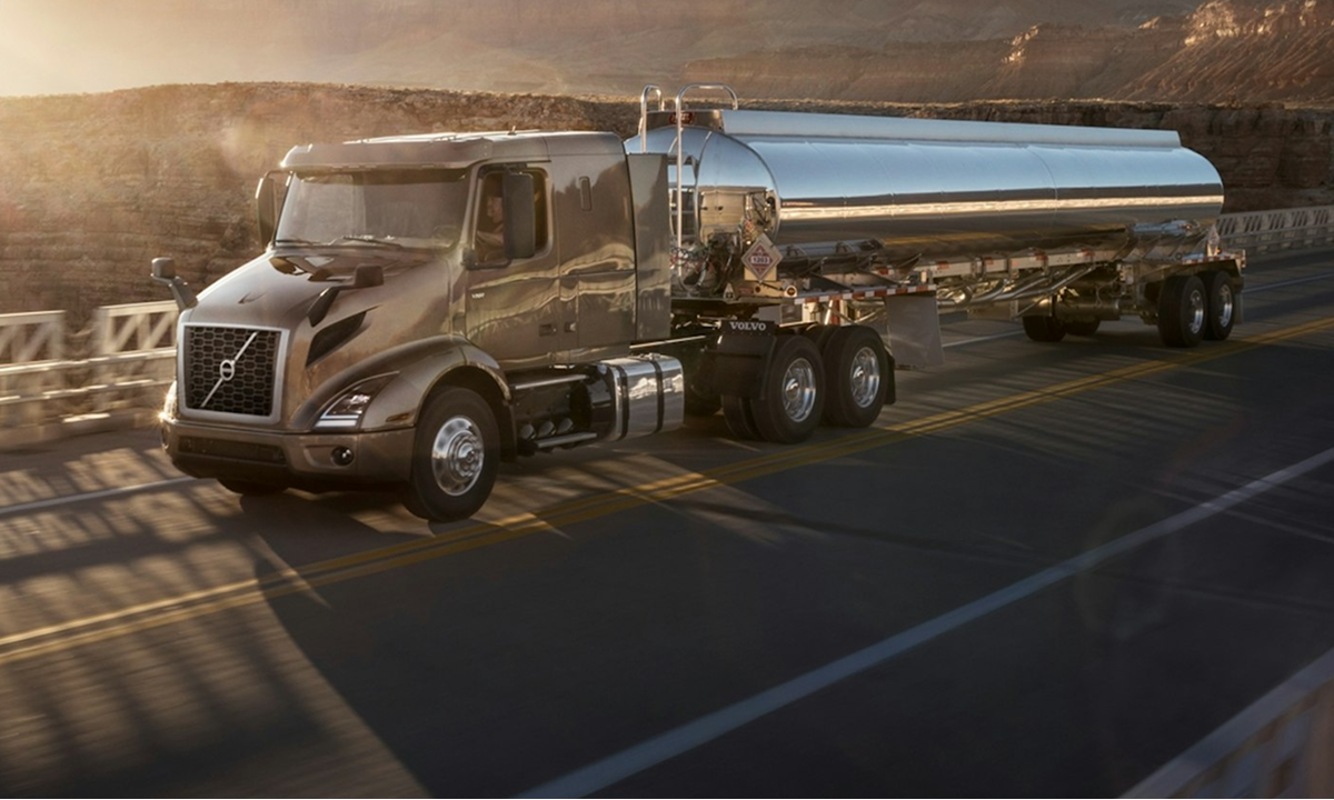 A large truck, surrounded by field and mountains