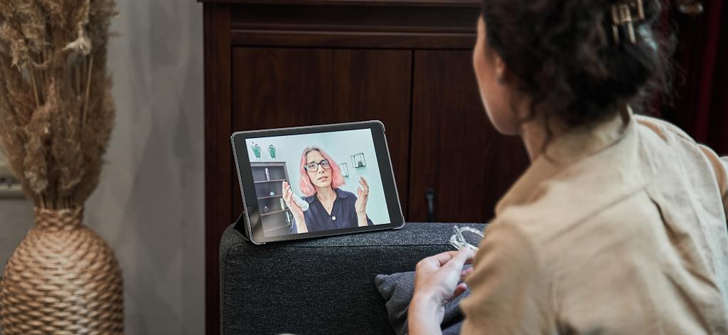 A woman sits on a couch, focused on a tablet computer in her hands