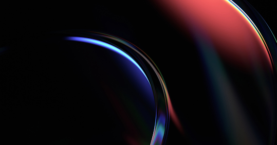 An abstract image featuring smooth, curved shapes in a dark background, illuminated by a blend of deep blue and red hues. The glossy, reflective surface of the shapes adds a sense of depth and dimension, with the colors softly transitioning from one to the other. The light accents highlight the curvature, creating a sleek, futuristic feel. The dark setting enhances the vibrancy of the colors, giving the image a dynamic and modern look, often associated with technology, data, and innovation.