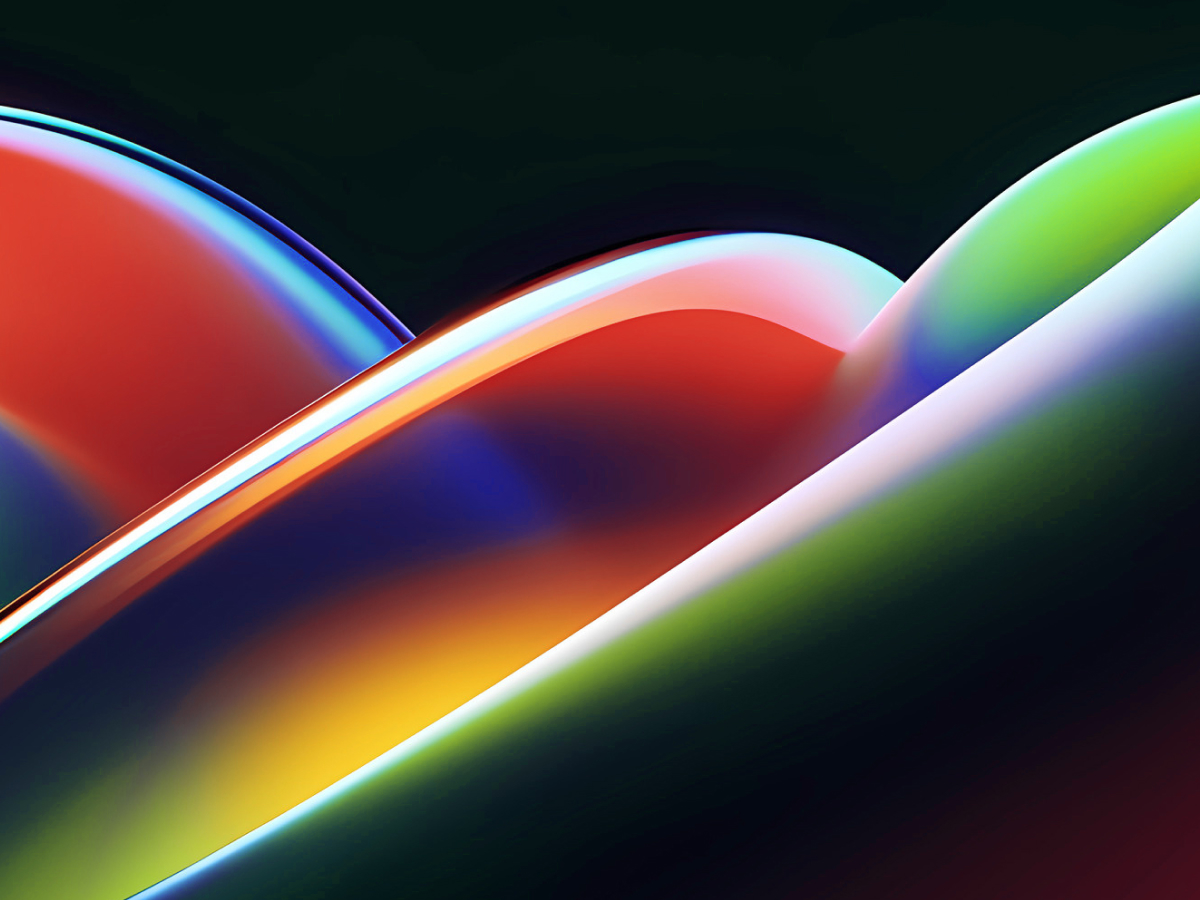 An abstract image featuring smooth, overlapping curved shapes with glossy, reflective surfaces. The colors transition from vibrant reds and oranges on the left to bright yellows, greens, and deep blues on the right.