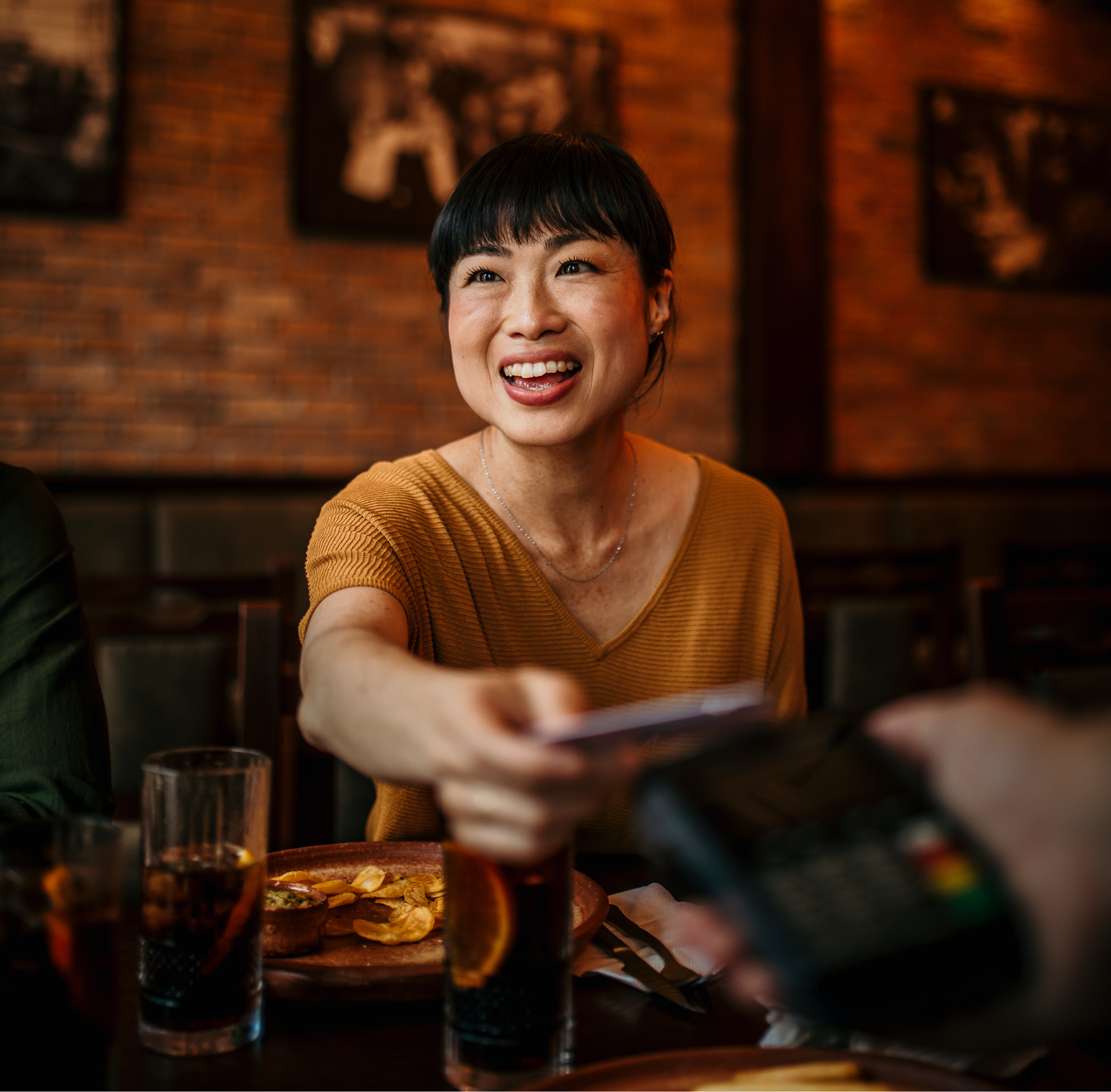 A woman smiles while holding a phone, looking cheerful and engaged