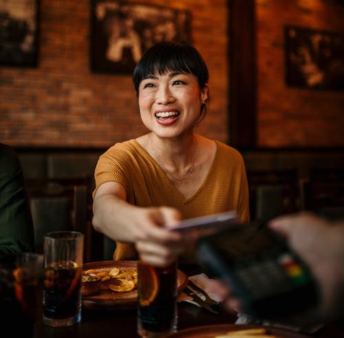 A woman smiles while holding a phone, looking cheerful and engaged