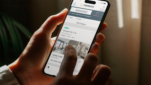 A person holds a smartphone displaying a real estate app