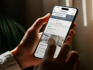 A person holds a smartphone displaying a real estate app