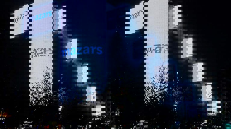 Image of a city at night featuring multiple digital screens with Mazars logo