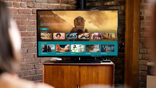 Two people sitting on a couch, watching a movie on a large television in a cozy living room setting.