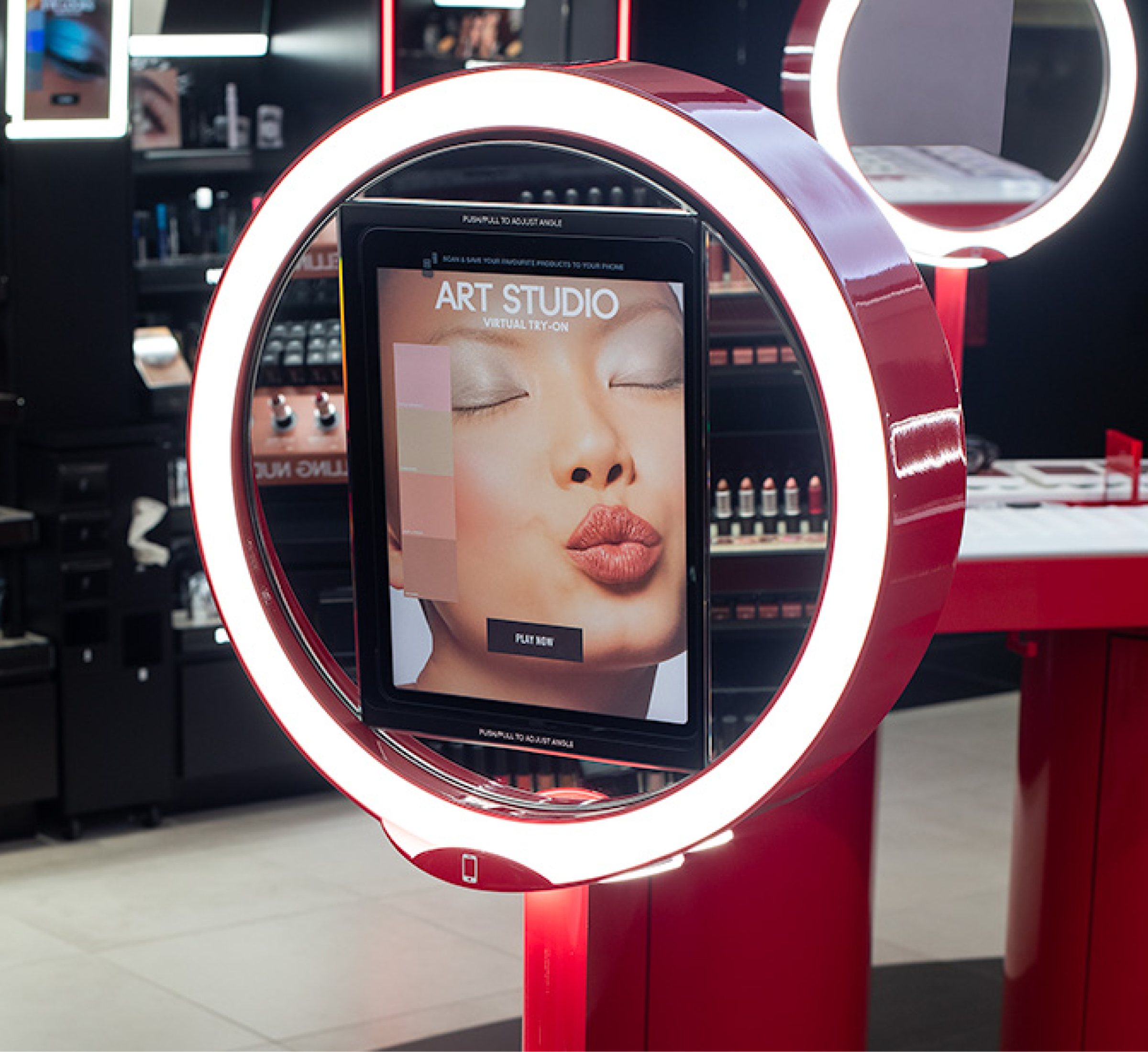 Circular LED-ring mounted touchscreen display in a luxury cosmetics store, showing a woman’s face and virtual makeup swatches for a “Virtual Try-On” Art Studio station.