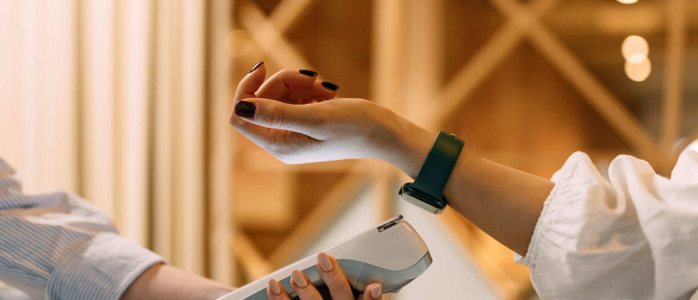Close-up of a hand holding a smartphone over a wrist resting on a wooden table, with the phone’s screen showing an augmented-reality overlay of a silver watch on the wrist.