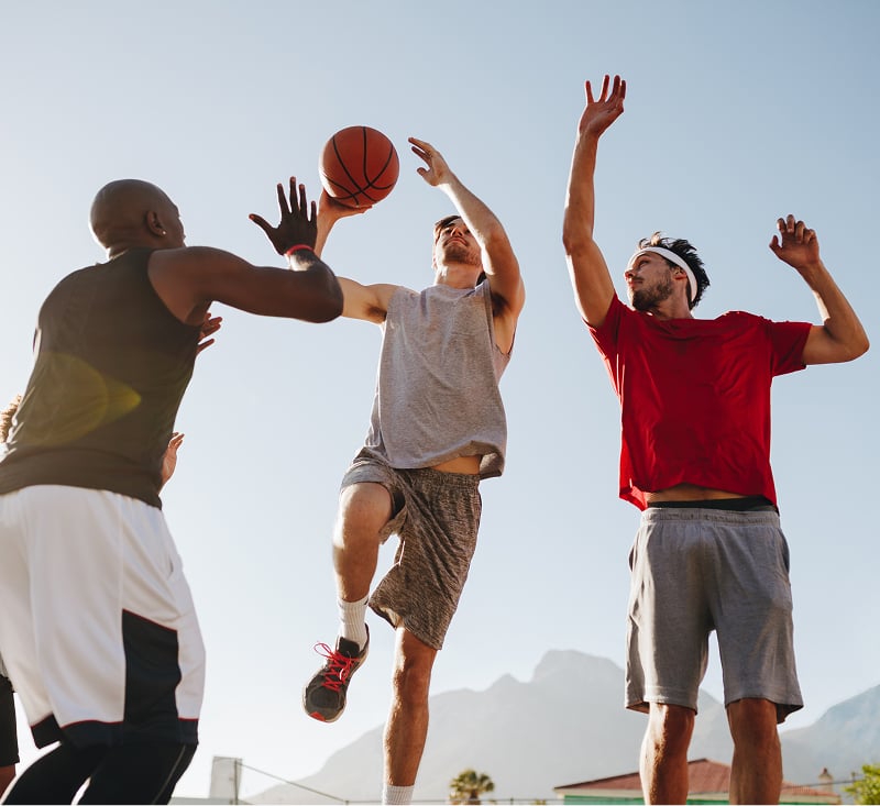 Three men engaged in a basketball game on a court, showcasing teamwork and athleticism.