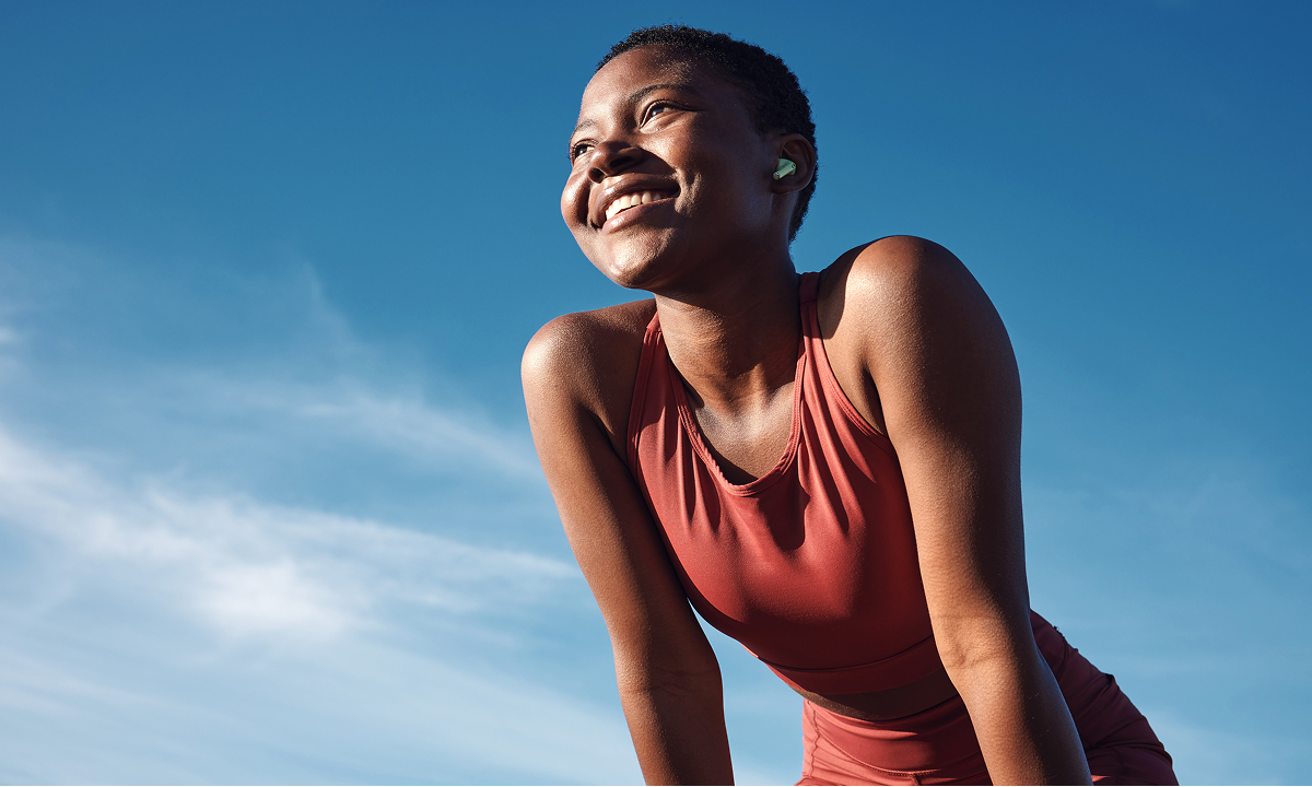  A smiling woman stands on a hill, enjoying the view and the fresh air. 