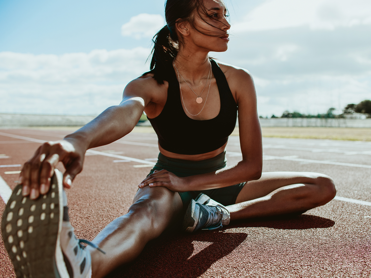 A woman performing a stretching exercise on a running track, preparing for her workout.  
