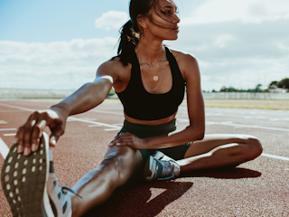 A woman performing a stretching exercise on a running track, preparing for her workout.