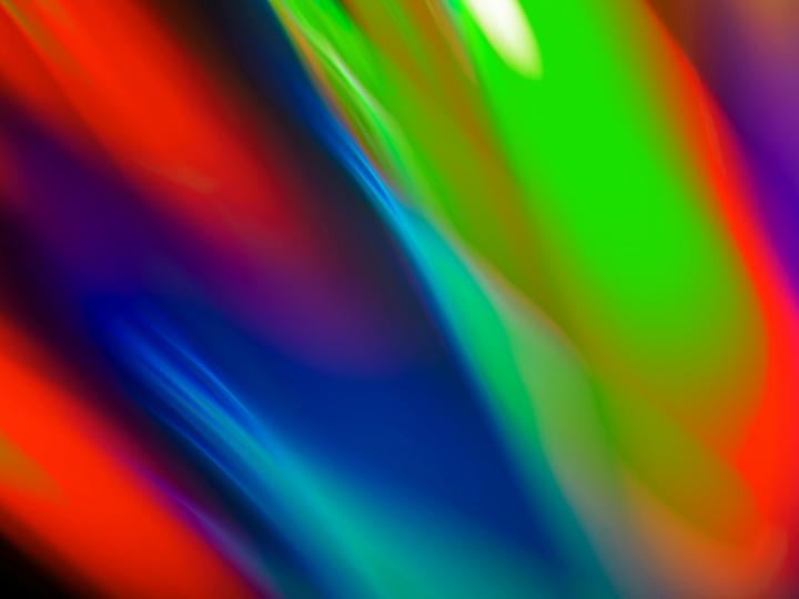 A vibrant and colorful abstract background with gradients of red, green, blue, and purple, blending smoothly with reflections, representing a dynamic and modern design.