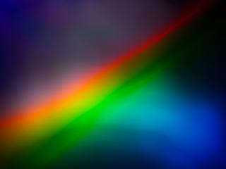 A vibrant abstract image featuring a diagonal gradient of bright colors resembling a rainbow light refraction effect.